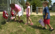 Michael Davis, 5, right, and Jessica Davis, 6, center, wait while their grandmother, Marie Gallagher places a flag at the fence outside the 25th Marine Regiment's 3rd Battalion Headquarters & Service Company, in Brook Park, Ohio, Wednesday, Aug. 3, 2005. Upon seeing on the news today that 14 more Marines were reported killed in Iraq Wednesday, the children asked Gallagher to take them to the base so they could place their flags there in honor of the dead marines. (AP Photo/Jamie-Andrea Yanak)